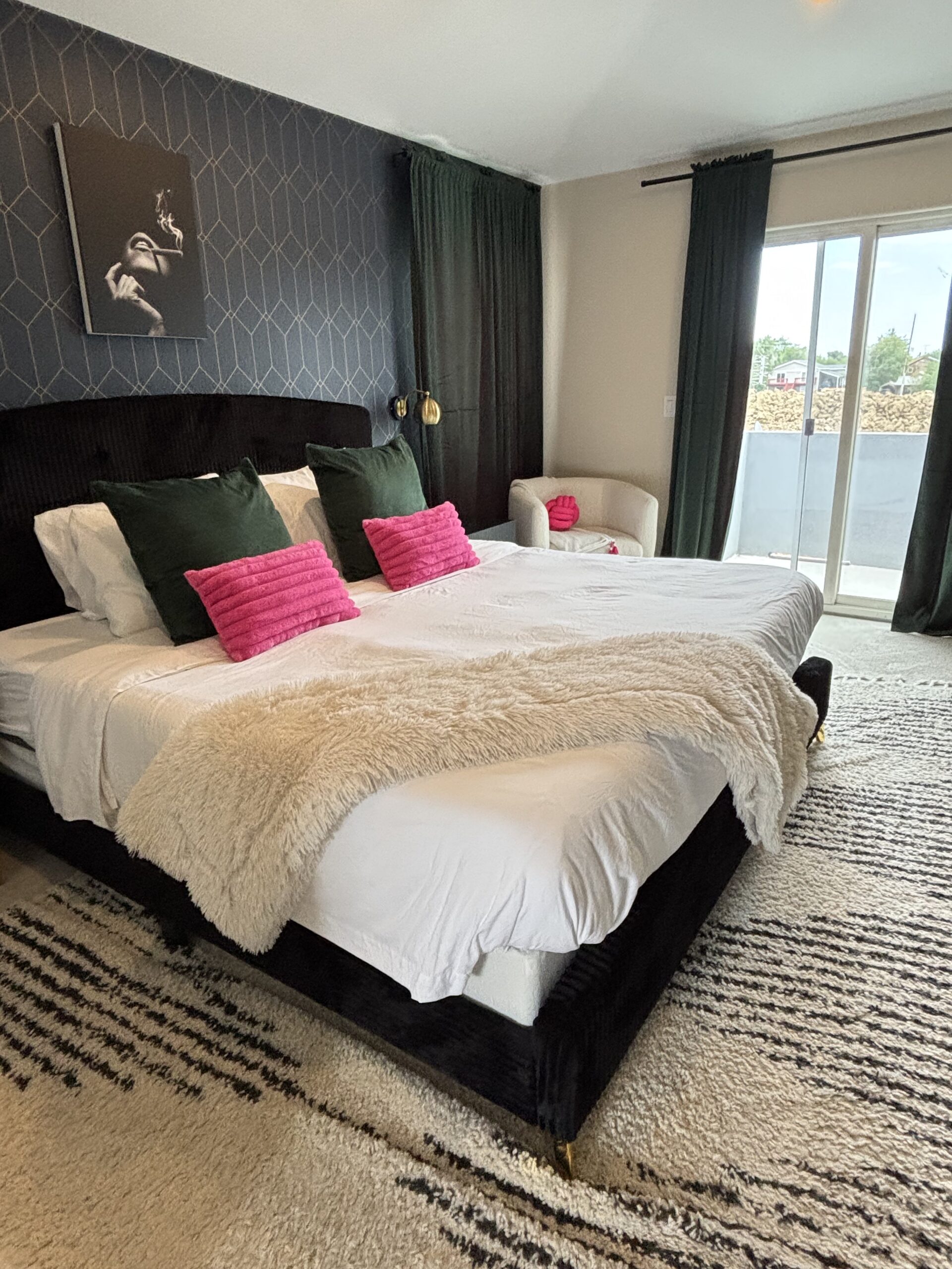 Luxurious, freshly cleaned bedroom in a vacation rental with crisp white bedding, plush green and pink pillows, and natural light highlighting a spotless, inviting space.